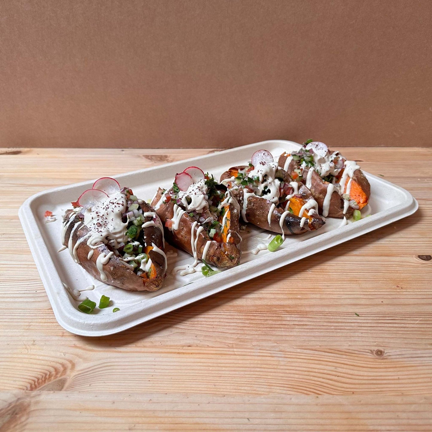A whole baked sweet potato filled with onion sumac and tahini sauce, Jaffa salad, radish, scallions and parsley