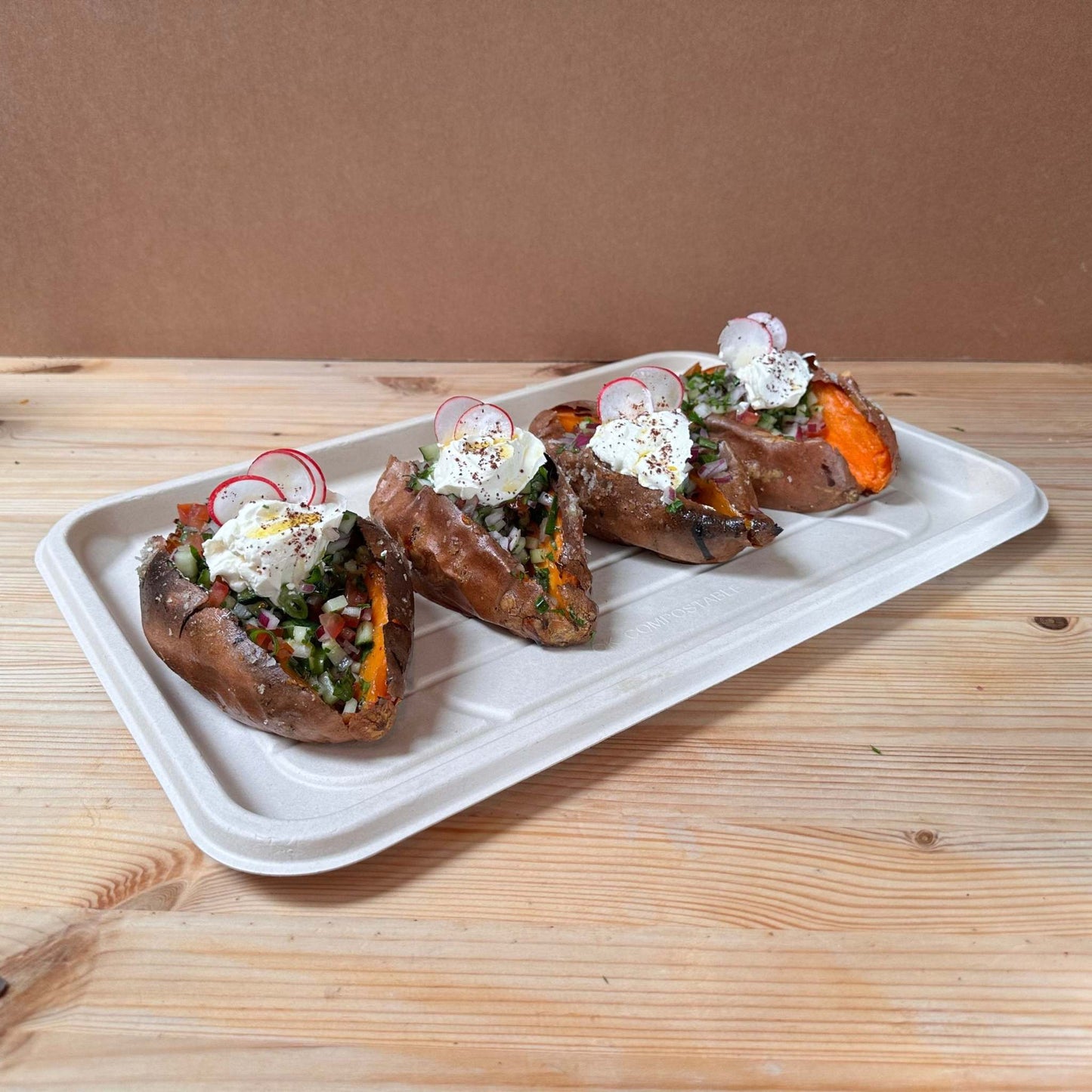 A whole baked sweet potato filled with onion sumac labneh sauce, Jaffa salad, radish, scallions and parsley. 