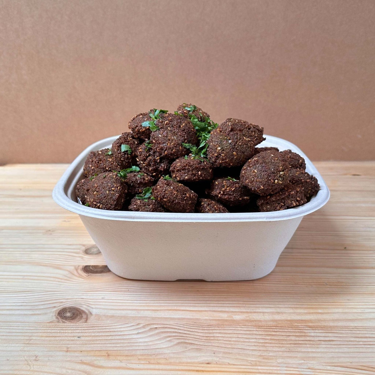 A bowl of crispy falafels served with a variety of dipping sauces, perfect for sharing at any event